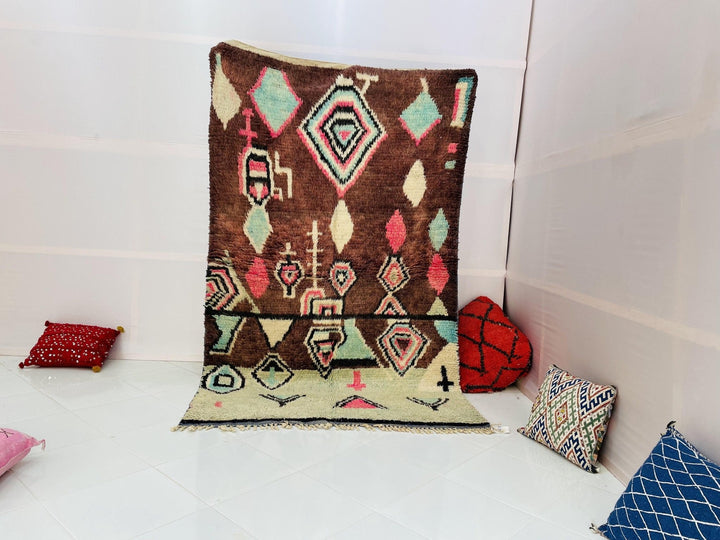 Lifestyle shot of a geometric Boujaad Moroccan rug in pink and green tones on a white background.