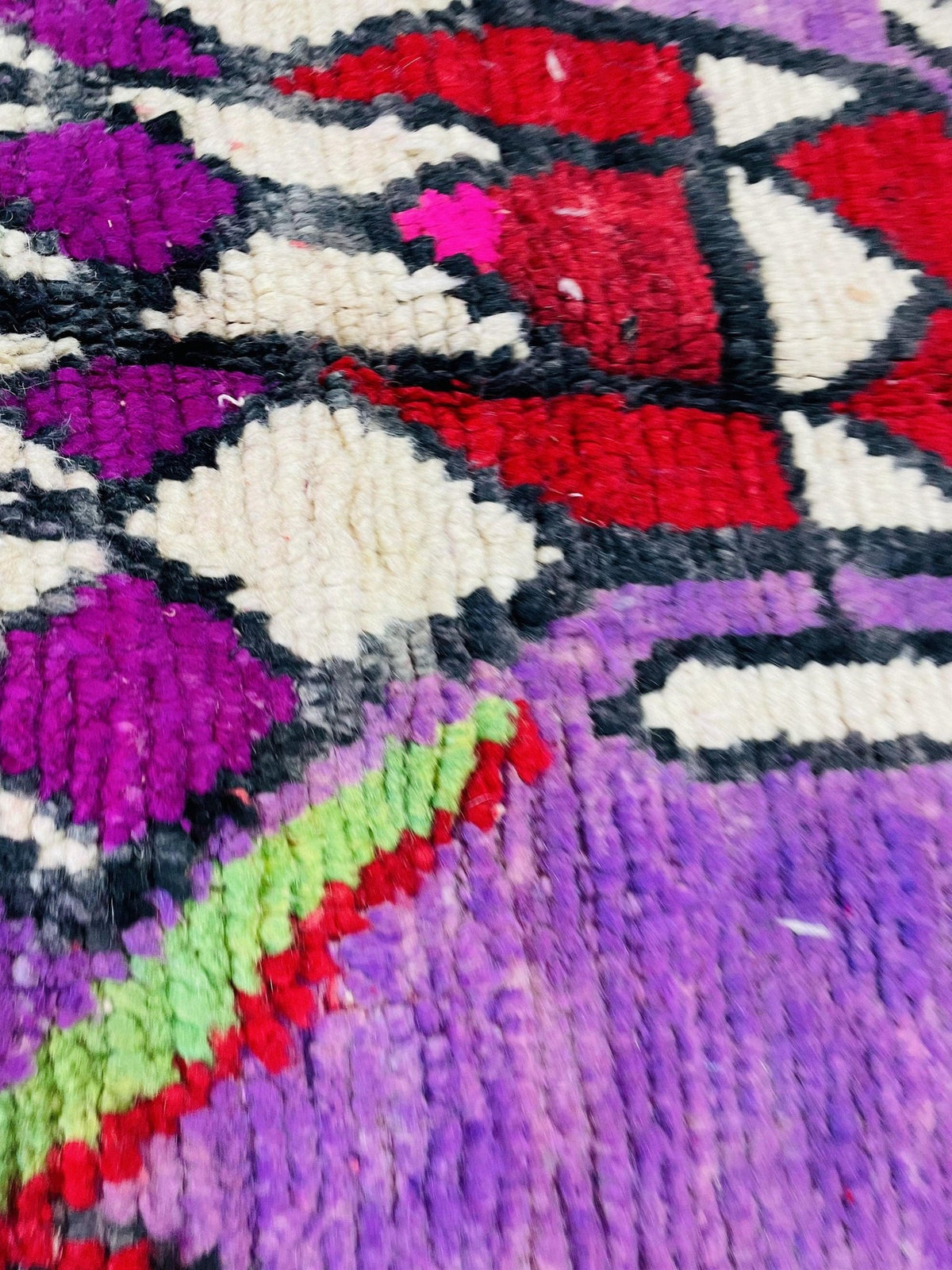 Detail shot of an abstract pattern on a Moroccan rug in purple, pink, red, and white colors.