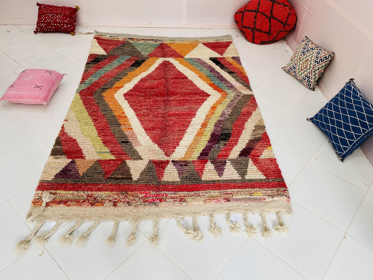 Lifestyle image showcasing a red and pink Moroccan rug with fringe detail and geometric patterns.
