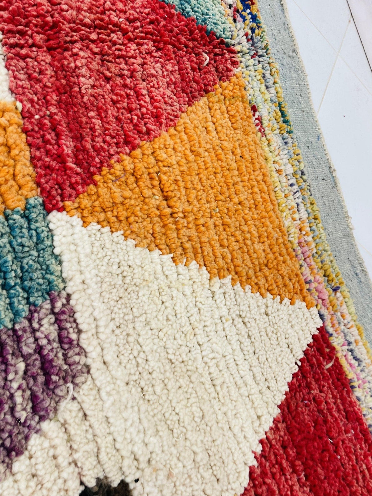 Detail view of a red and pink Moroccan rug with geometric patterns against a white background.