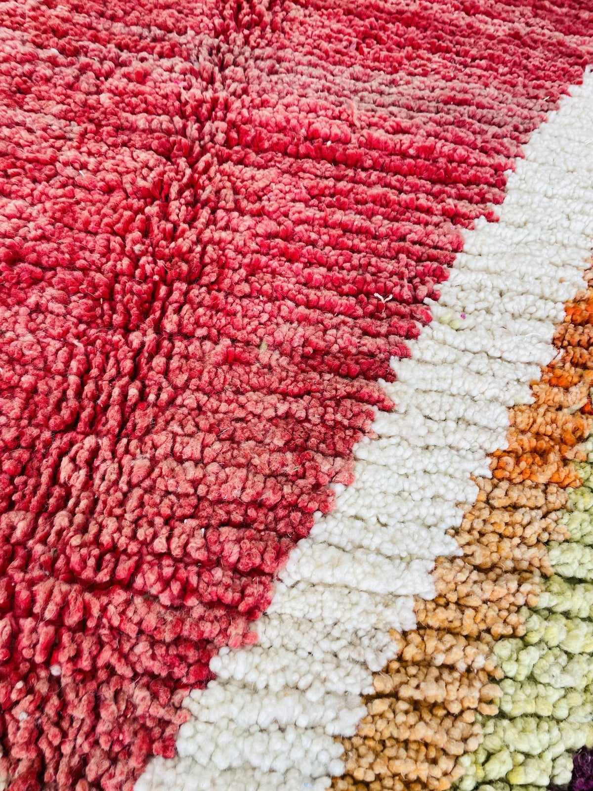 Close-up view highlighting the textured fibers of a red and pink Moroccan rug.