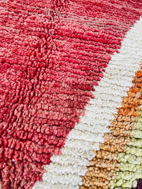 Close-up view highlighting the textured fibers of a red and pink Moroccan rug.