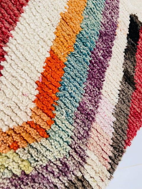 Detail shot of a red and pink Moroccan rug featuring an abstract design on a white background.