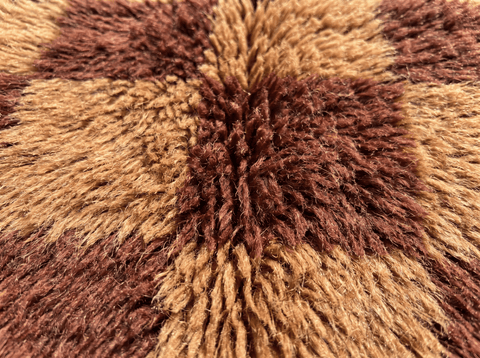Close-up detail of a burgundy checkered Moroccan rug highlighting its geometric pattern on a white background.