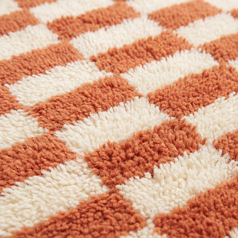 Detail view of the checkered terracotta rug highlighting its plush texture against a white background.