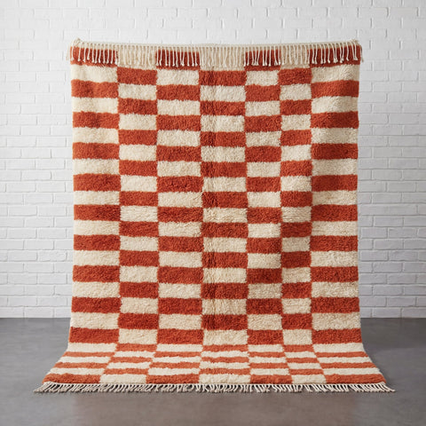 Lifestyle shot of a checkered terracotta rug in a living room setting with natural background.