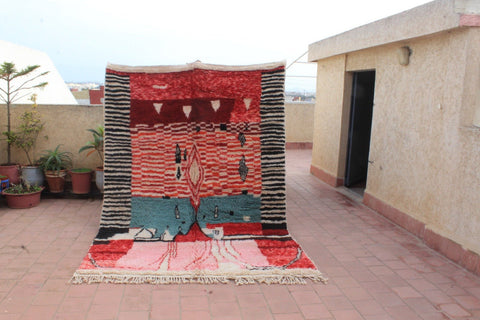 Lifestyle shot of a Moroccan rug featuring intricate Azilal motifs in red, blue, and black.