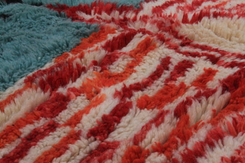 Detail close-up of a Moroccan rug showcasing colorful patterns in red, white, and blue.