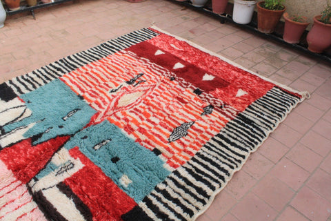 Detail close-up of a Moroccan rug displaying geometric patterns in red, blue, black, and white.