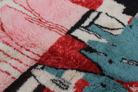 Detail close-up of a Moroccan rug featuring intricate motifs in pink, red, and blue.