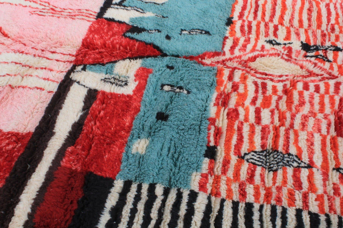 Detail close-up of a Moroccan rug with an abstract design in red, blue, black, and white.