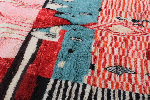 Detail close-up of a Moroccan rug with an abstract design in red, blue, black, and white.