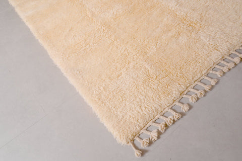 Close-up detail of the off-white Moroccan rug highlighting its fringe detail and soft texture.