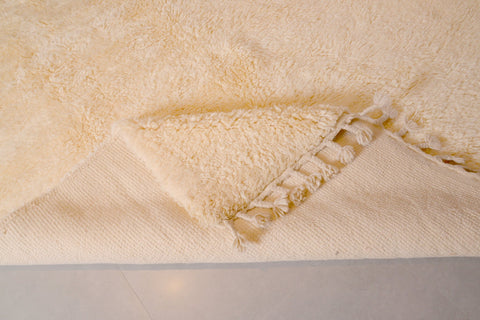 Detail of the off-white Moroccan rug with a geometric pattern and textured surface.