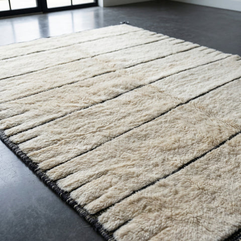 Detail close-up of a cream tufted rug featuring a striped pattern on a studio background.