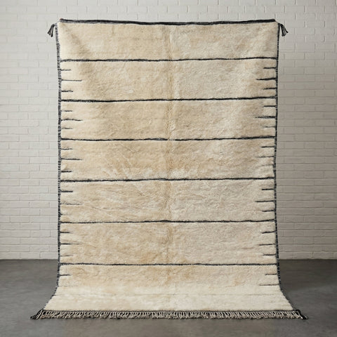 Front view of a cream tufted Moroccan rug featuring a striped design against a studio backdrop.