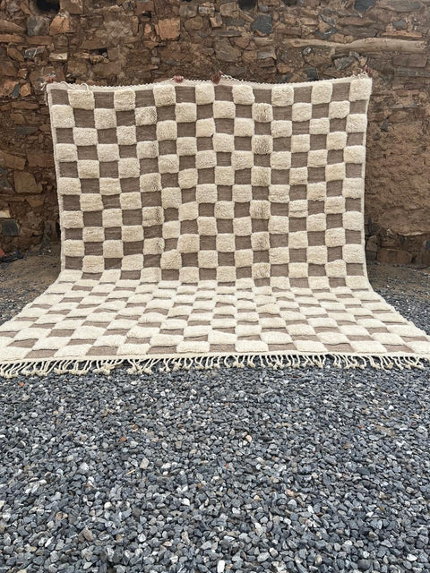 Lifestyle shot of the cream checkered Moroccan rug featuring a geometric pattern in a natural setting.
