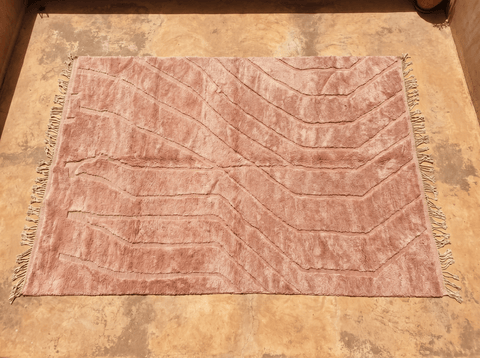 Detail close-up of a dusty rose Moroccan rug displaying a patterned design in pink and cream hues.