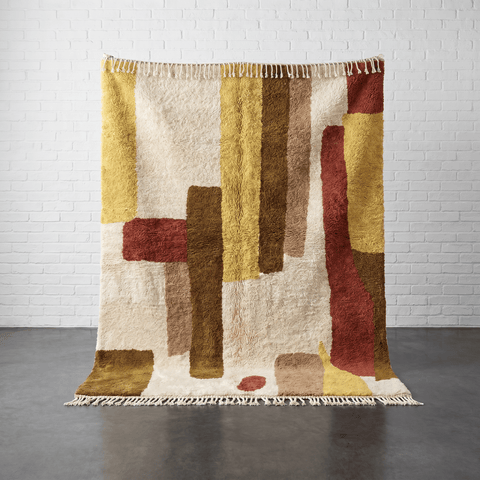 Detail view of the beige and brown Moroccan rug featuring geometric patterns and fringe edges.