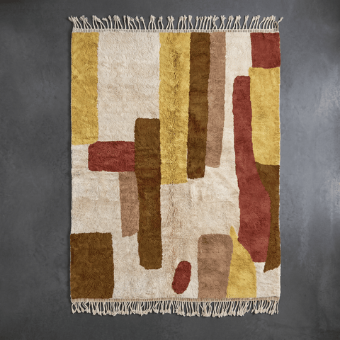 Close-up of the yellow and red geometric patterns on the Moroccan rug with fringe edges.