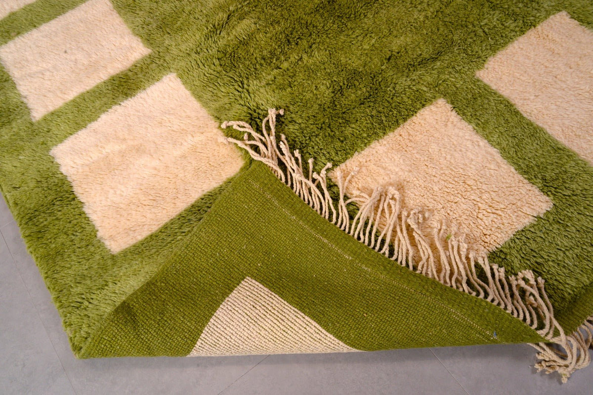 Close-up detail of the olive green Moroccan rug focusing on its geometric pattern and fringe edges.