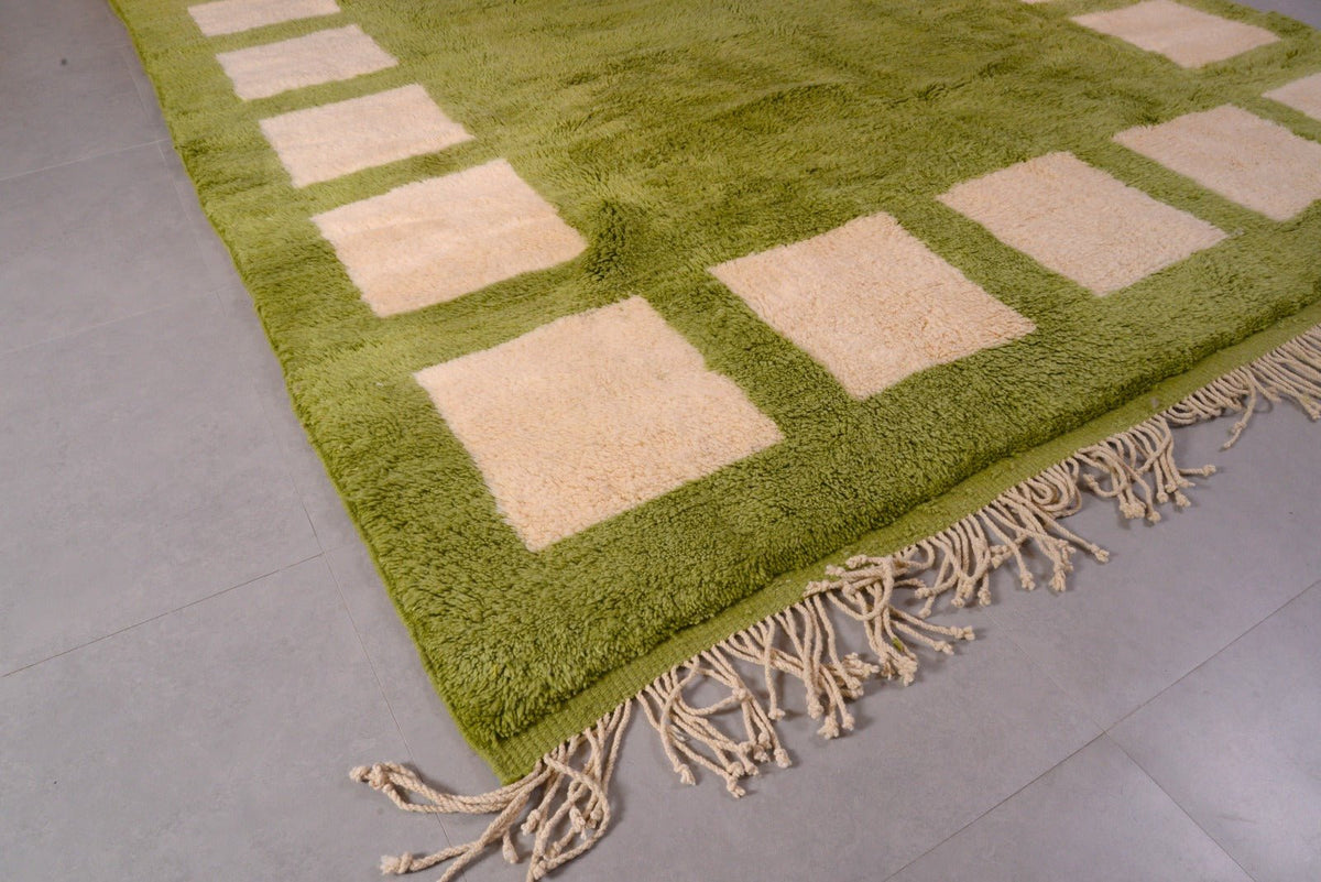 Close-up detail of the olive green Moroccan rug emphasizing its geometric design and fringe edges.