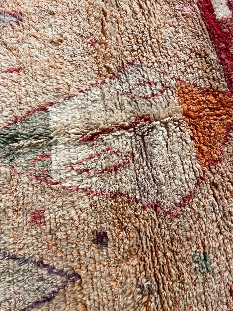 Detail close-up of the textured pattern on a vintage Moroccan rug in red and orange.