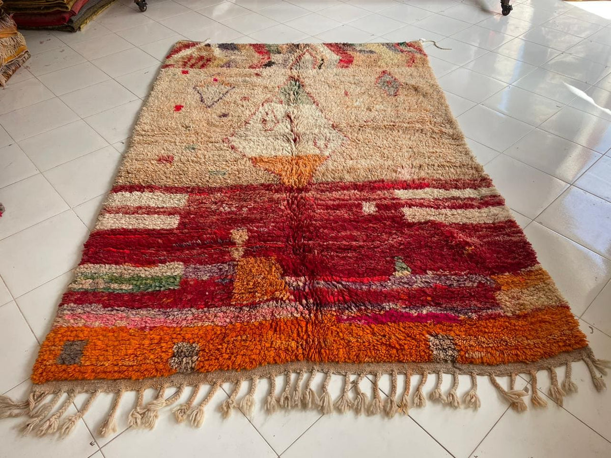 Front view of a vintage Moroccan rug showcasing red and orange hues with fringe edges.