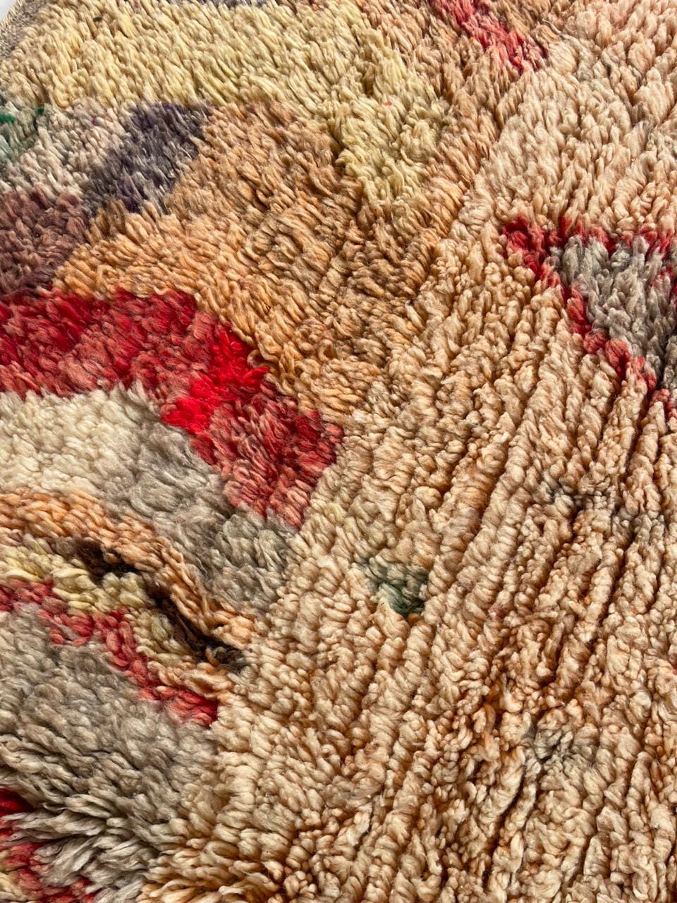 Front view of a vintage Moroccan rug displaying bold patterns in red, orange, and cream.