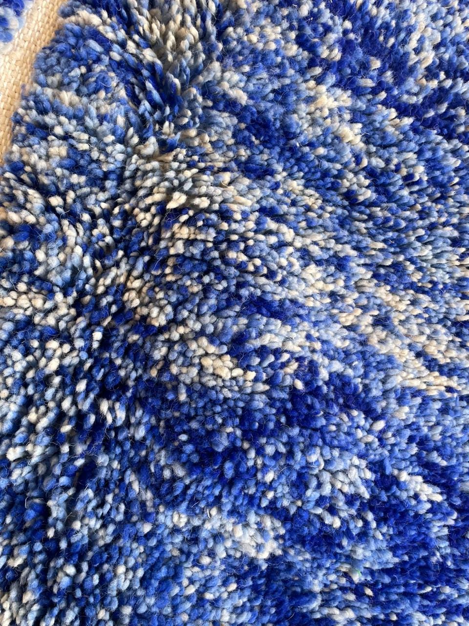 Close-up detail of a blue wool rug showing its intricate pattern.