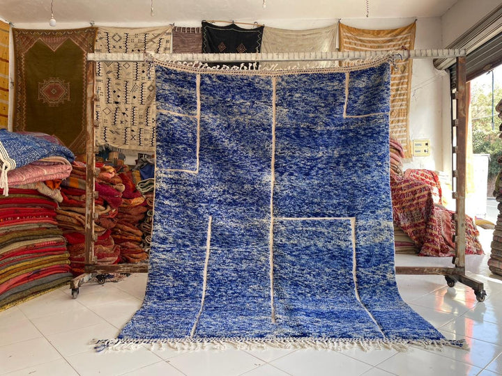Lifestyle shot of a blue Moroccan rug with a textured pattern on a natural background.