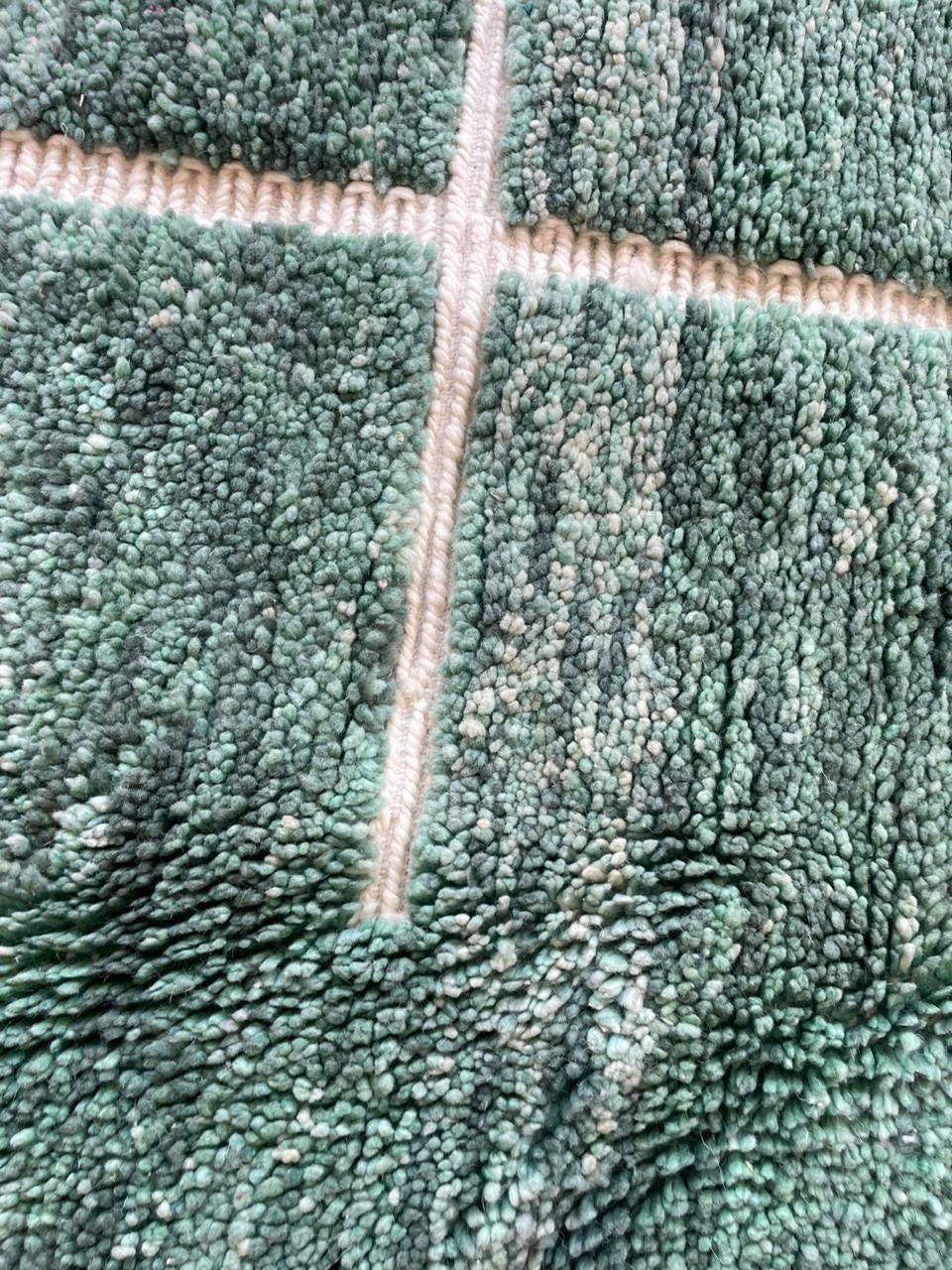 Close-up view of the green vintage Beni Ourain Moroccan rug featuring a geometric pattern and textured surface.