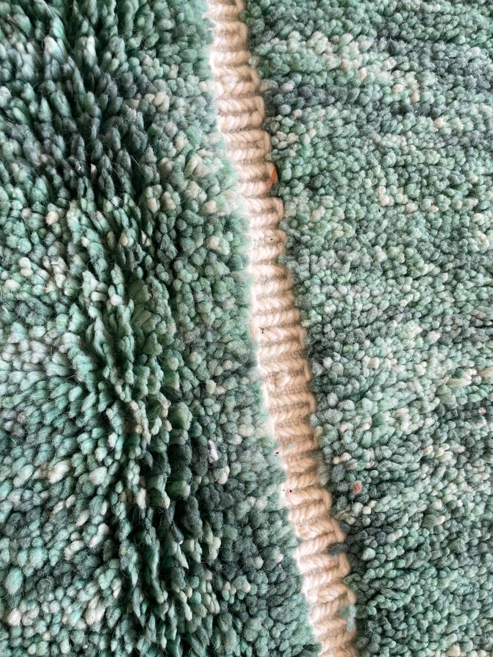 Close-up detail of the green vintage Beni Ourain Moroccan rug highlighting its geometric pattern.