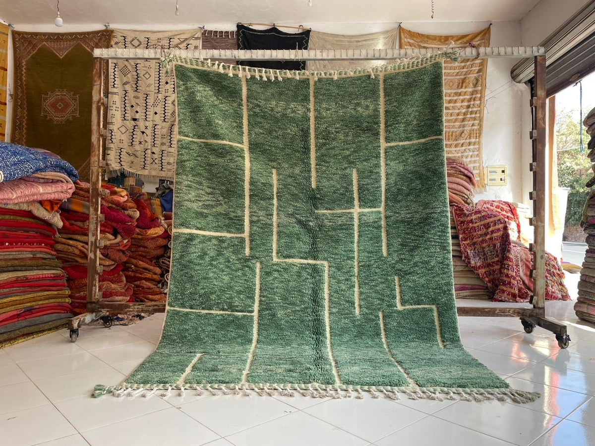 Lifestyle shot of a green vintage Beni Ourain Moroccan rug with geometric patterns and fringe edges.