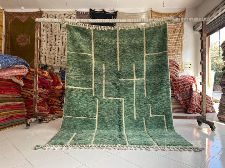 Lifestyle shot of a green vintage Beni Ourain Moroccan rug with geometric patterns and fringe edges.