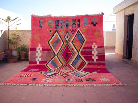 Lifestyle shot of a pink Moroccan rug with geometric patterns in a natural setting.