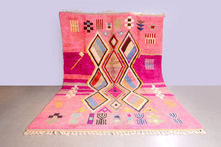 Lifestyle shot of a pink Moroccan rug featuring geometric patterns on a natural background.