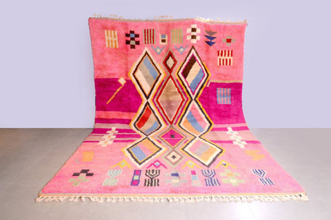 Lifestyle shot of a pink Moroccan rug featuring geometric patterns on a natural background.
