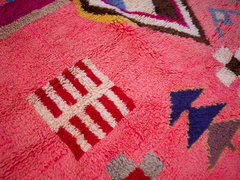 Detail shot of a pink Moroccan rug highlighting geometric patterns and soft texture.