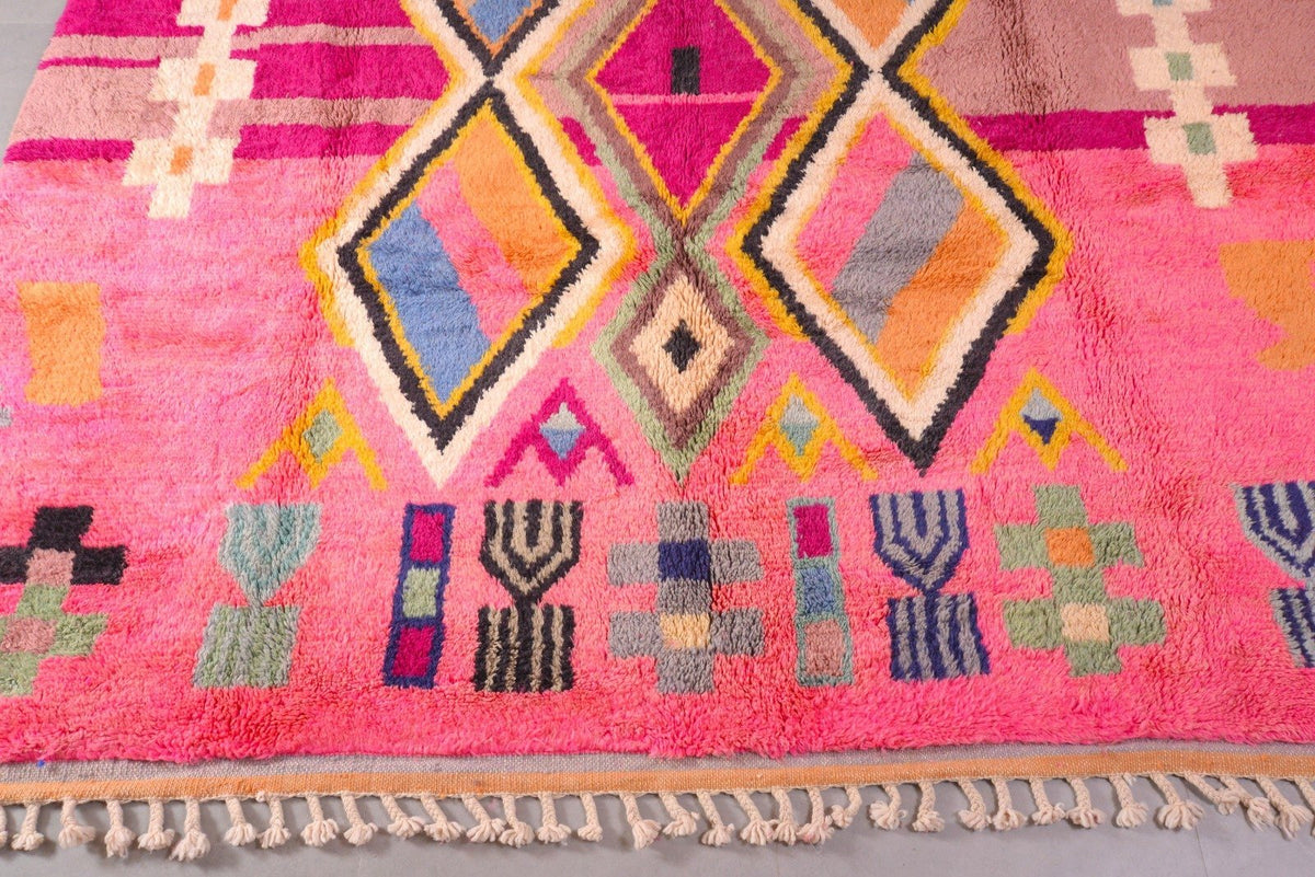 Detail close-up of a pink Moroccan rug with geometric patterns on a natural background.