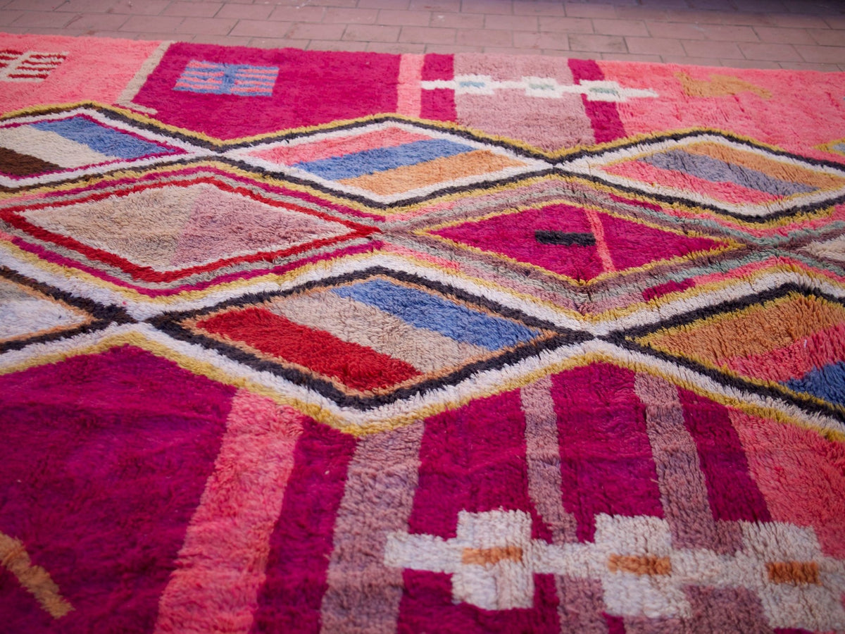 Close-up of a pink Moroccan rug with diamond patterns in a natural setting.