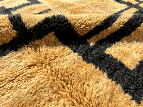 Close-up detail of a golden yellow Moroccan rug featuring a geometric pattern and soft texture.