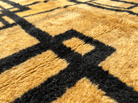 Close-up detail of the geometric design on a golden yellow Moroccan rug highlighting its texture.