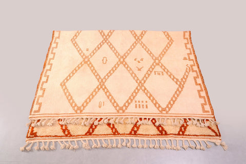 Detail close-up of the diamond pattern rug highlighting the cream and orange colors and fringed edges.