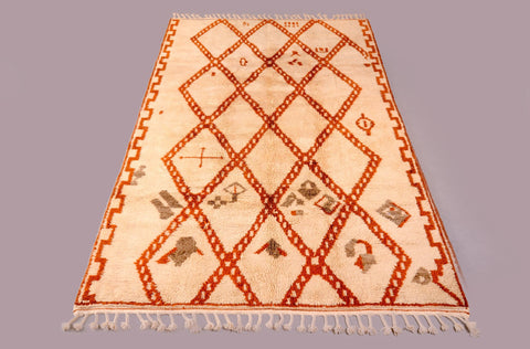 Lifestyle view of the diamond pattern rug showcasing cream and orange colors with fringed edges.