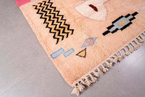Close-up detail of the pink Moroccan rug with fringe edges and geometric patterns.
