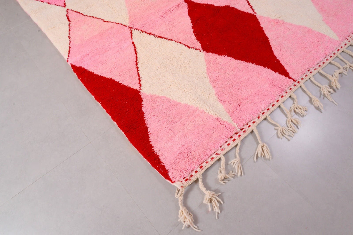 Detail close-up of the pink Beni Ourain rug featuring fringe edges in a studio setting.