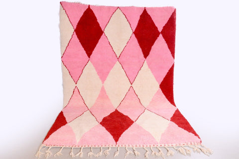 Lifestyle shot of the pink diamond design rug with fringe edges on a white background.