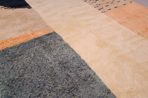 Close-up of the geometric design and textured patterns on the beige, gray, and brown rug.