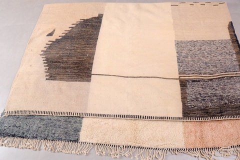 Detail view of the geometric design and textured patterns on the beige, gray, and brown rug.